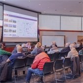 Residents attend a Coffee with the Village President meeting with a presentation displayed on a screen