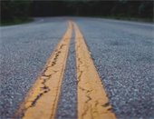 close up photo of asphalt road with yellow paint lines