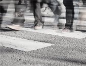 black and white photo of people's legs walking across a crosswalk