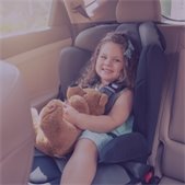 photo of smiling girl in front facing car seat holding teddy bear