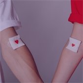 two forearms with bandaids that have red heart drawn on them