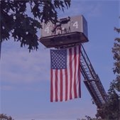 photo of US flag in sky and hanging from Tower Ladder