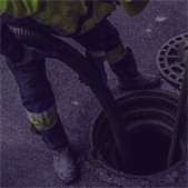 photo of construction worker leading tube down sewer manhole