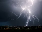 photo of night sky lit up by multiple lightning strikes