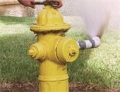 yellow fire hydrant being serviced with water spraying out