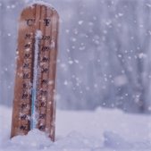 Wooden thermometer showing cold temperatures in falling snow