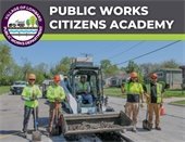 group photo of streets crew holding shovels in front of yellow tractor