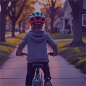 back of child riding bicycle wearing helmet