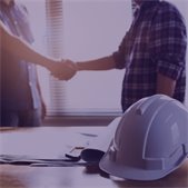 photo of two people shaking hands and construction hat on table in front of them