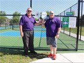 park district board president and village president holding paddles up, smiling in front of pickle ball courts
