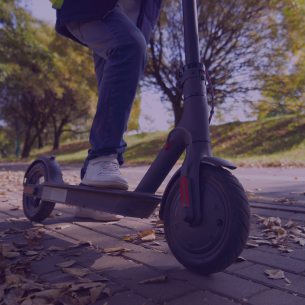 close up photo of person riding escooter on sidewalk 