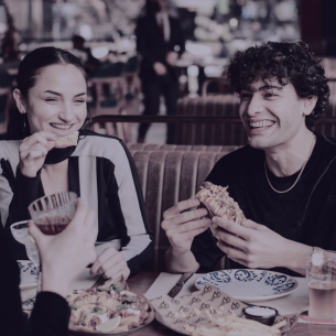 Two people smiling and enjoying a meal together at a restaurant