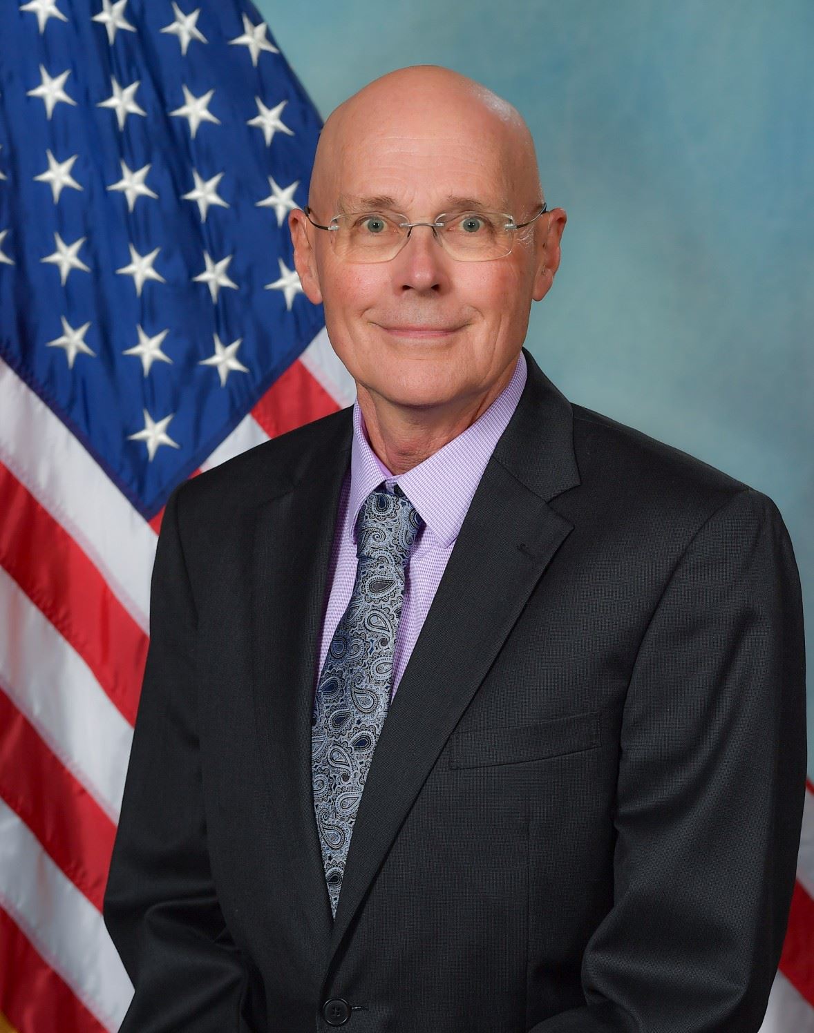 Headshot of Trustee Patrick Egan with US flag in background
